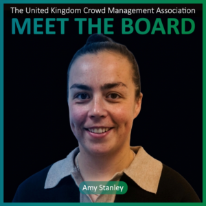 A woman with brown hair in a bun smiles at the camera. Text above reads MEET THE BOARD, highlighting one of the dedicated Board Members, and her name, Amy Stanley, is displayed at the bottom.