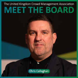 A man in a suit poses in front of a background with text reading Meet the Board and Chris Callaghan for the United Kingdom Crowd Management Association, highlighting him as one of the esteemed Board Members.