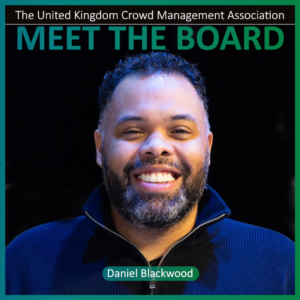 Portrait of a smiling man with a beard and dark jacket. Text reads The United Kingdom Crowd Management Association MEET THE BOARD and Board Members Daniel Blackwood.
