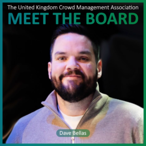 A bearded man in a light jumper stands in front of a dark background. Text reads: The United Kingdom Crowd Management Association, Meet The Board Members, Dave Bellas.