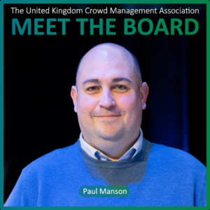 A man in a blue jumper stands in front of a dark background. Text reads: The United Kingdom Crowd Management Association MEET THE BOARD and Paul Manson, highlighting one of the dedicated Board Members.
